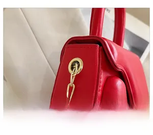 Detail of red leather mini bag showing glossy texture and gold metal chain links