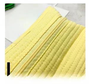 Detail of a bright yellow quilted canvas backpack featuring a smooth resin zipper closure