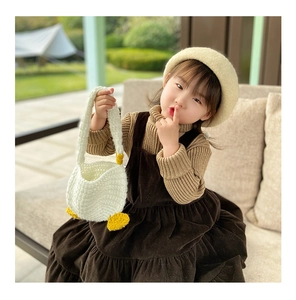 Detailed close-up of handmade white crochet goose bag with yellow duck feet and beak