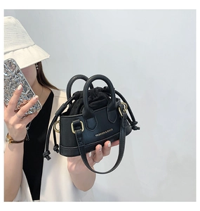 Detail of mini black shell bag with drawstring inner pouch and gold fashion text
