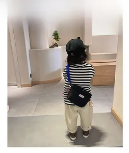 Vue arrière d'un enfant portant un sac matelassé noir avec bandoulière bleue plissée