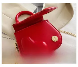 Detail shot of the magnetic snap closure on a red leather heart mini handbag