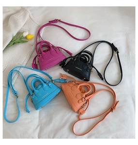 Flat lay of colorful mini shell crossbody bags in rose, black, blue, and orange tones