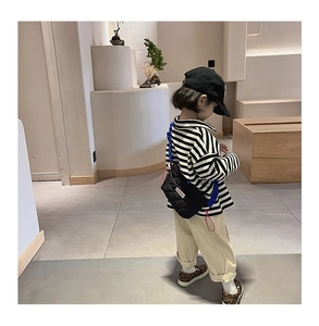 Détail du sac bandoulière matelassé noir pour enfant avec sangle bleue et accents rouges
