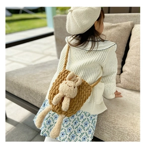 Détail d'un sac en tricot kaki avec lapin en peluche porté en bandoulière par un enfant