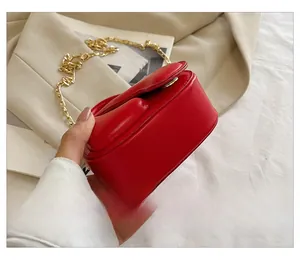 Close-up of red mini square chain bag with golden hardware and smooth leather texture