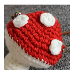 Close-up of handmade crochet mushroom pendant with red spotted cap and white stem detail