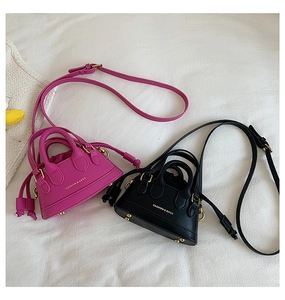 Detail of mini textured faux leather shell bags in rose red and black with gold rivets