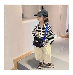 Détail d'un enfant portant un polo rayé et un pantalon beige décontracté avec un sac bandoulière