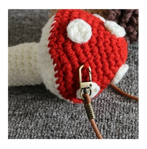 Macro detail of hand-crocheted mushroom pendant with metal clasp and leather strap