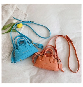 Detail of mini shell crossbody bags in blue and orange with drawstring inner and top handles