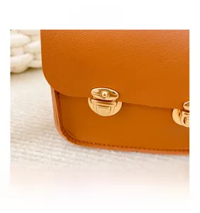 Vue détaillée des boucles en métal doré sur le sac en cuir texturé orange-marron