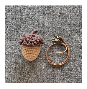 Macro shot of handmade acorn crochet bag with brown leather strap and metal buckle
