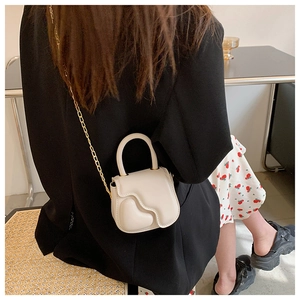 Detail of off-white leather mini handbag with heart embossed design and gold chain strap