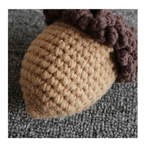 Macro detail of hand-knitted acorn bag showing camel yarn texture and brown cap
