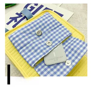 Detail of kids backpack featuring a yellow canvas body and blue plaid front magnetic pocket