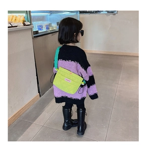 Vue de dos d'un enfant portant un sac bandoulière matelassé vert fluo sur un pull violet