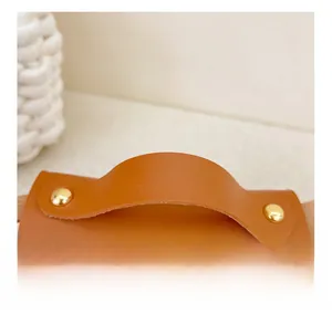 Détail de la poignée en similicuir avec rivets dorés sur un sac rétro orange vif
