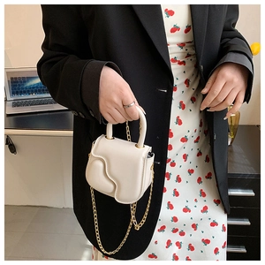 Detail of cream mini handbag with wavy flap, round handle and gold chain strap