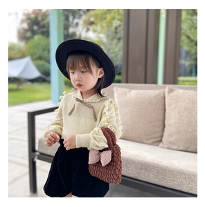 Close-up of brown knitted handbag with plaid bow on a stylish child's winter outfit