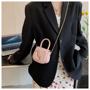 Close-up of pink mini crossbody bag with wavy flap design and fine metal chain strap