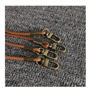 Detail of deep brown leather cords with antique brass lobster clasps and metal sleeves