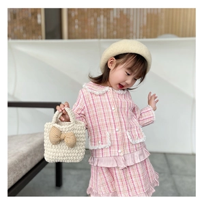 Detail of pink plaid tweed outfit featuring a white fringe hem and knit handbag