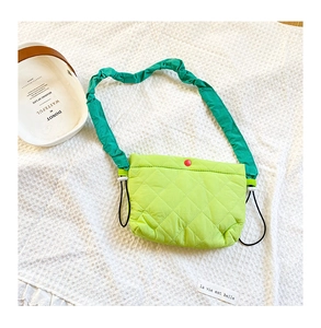 Détail du sac bandoulière matelassé vert néon avec bouton pression rouge et bandoulière à volants