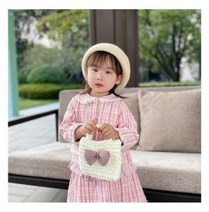 Detail of cream crochet knit handbag with brown checkered bow for toddler girls