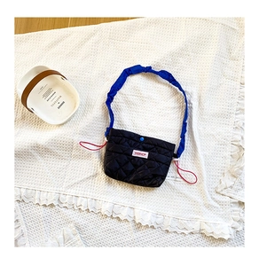 Détail du sac matelassé noir avec bandoulière bleue froncée et cordon rouge