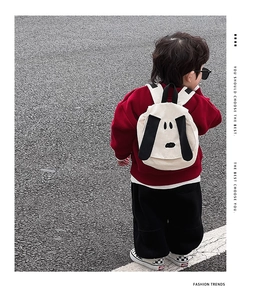 Detail of cute puppy cartoon backpack on a boy in a red hoodie during outdoor activity