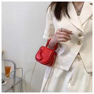 Detail of red mini crossbody bag with 3D wave pattern and golden chain strap