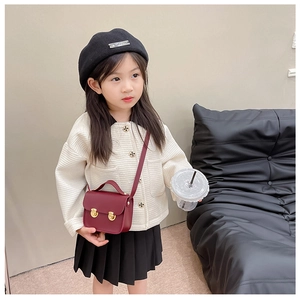 Détail d'un mini sac bandoulière bordeaux en cuir avec boucles dorées sur une fille