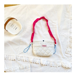 Détail du sac matelassé blanc avec bandoulière à volants rose vif et cordons de serrage latéraux