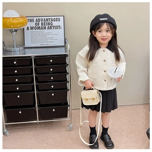 Détail de la veste gaufrée blanche et de la jupe plissée noire pour petite fille