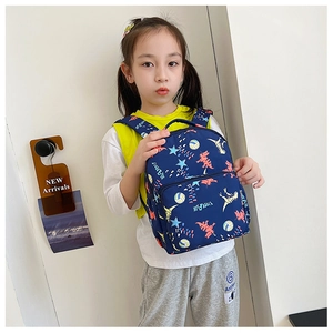 Detail of blue canvas kids backpack featuring cartoon dinosaur prints and zippered front pocket