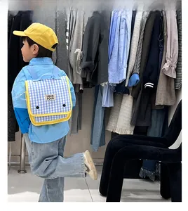 Blue and white checkered kids backpack with yellow piping worn by a young boy