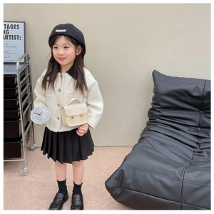 Tenue de fille avec veste matelassée blanche, jupe plissée noire et mini sac à bandoulière