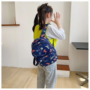 Detail of cute navy dinosaur backpack with cartoon print on a little girl for size scale