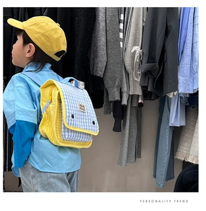Detail view of colorful gingham and yellow quilted kids backpack worn by a young boy