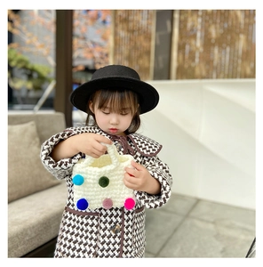 Detailed close-up of handmade crochet bag with colorful plush pom-poms for girls