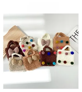 Detailed flat lay of colorful handmade knit mini handbags with cute bows and pom-poms