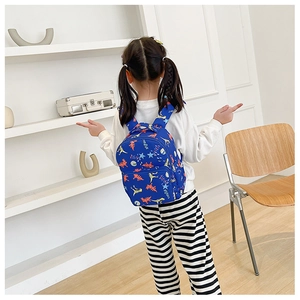 Toddler wearing a blue backpack with cute cartoon dinosaur prints and star patterns
