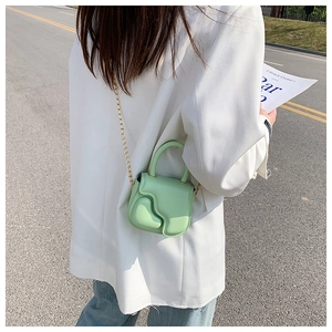 Mint green mini crossbody bag with gold chain strap shown on a white blazer outfit