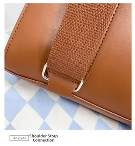 Detail view of reinforced fabric shoulder strap and metal ring on brown PU leather backpack