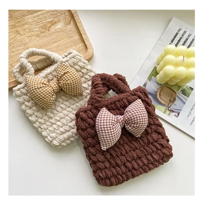Detail of handmade knit plush mini handbags with plaid bows in cream and brown colors
