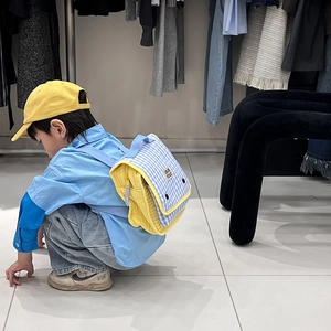 Kids yellow and blue canvas backpack with checkered flap shown on child model