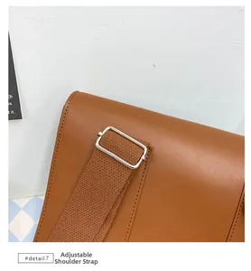 Detail view of adjustable brown fabric shoulder strap with silver metal buckle on PU backpack