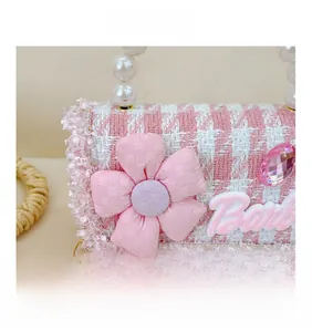 Detail of pink plaid tweed bag with pearl handle and floral diamond embellishments