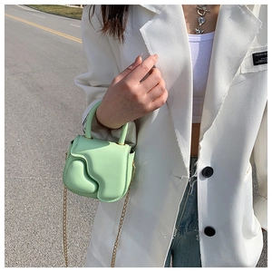 Detail of mint green mini bag with heart relief design and gold chain strap